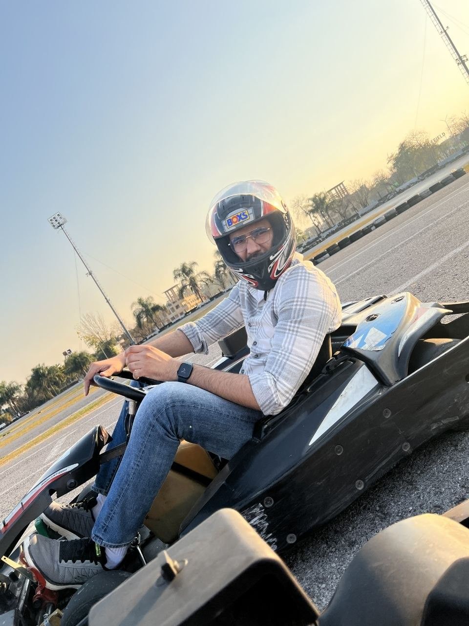 Faaiz in a helmet, sitting in a go-kart at sunset