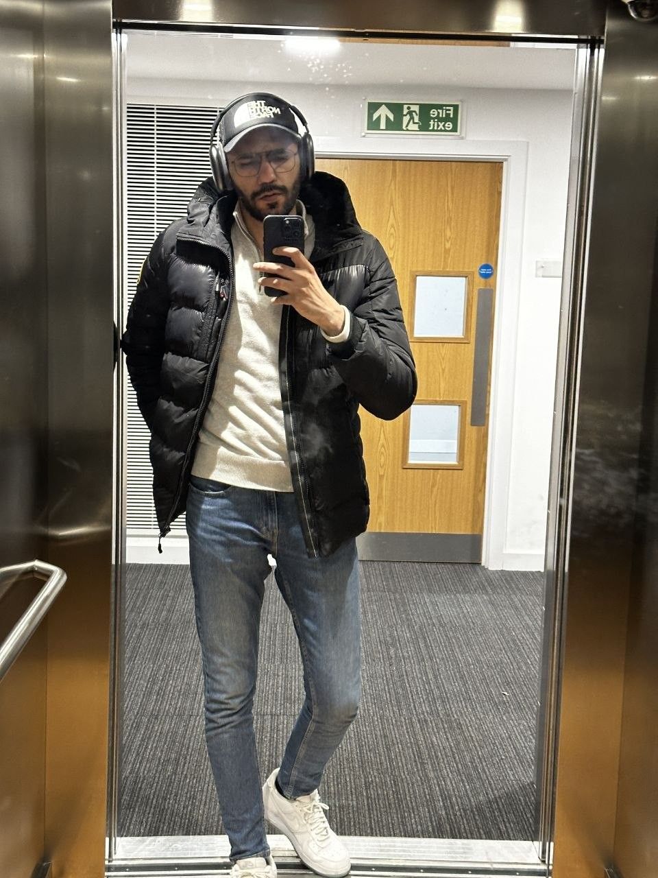 Faaiz in a winter puffer jacket, mirror selfie in a lift