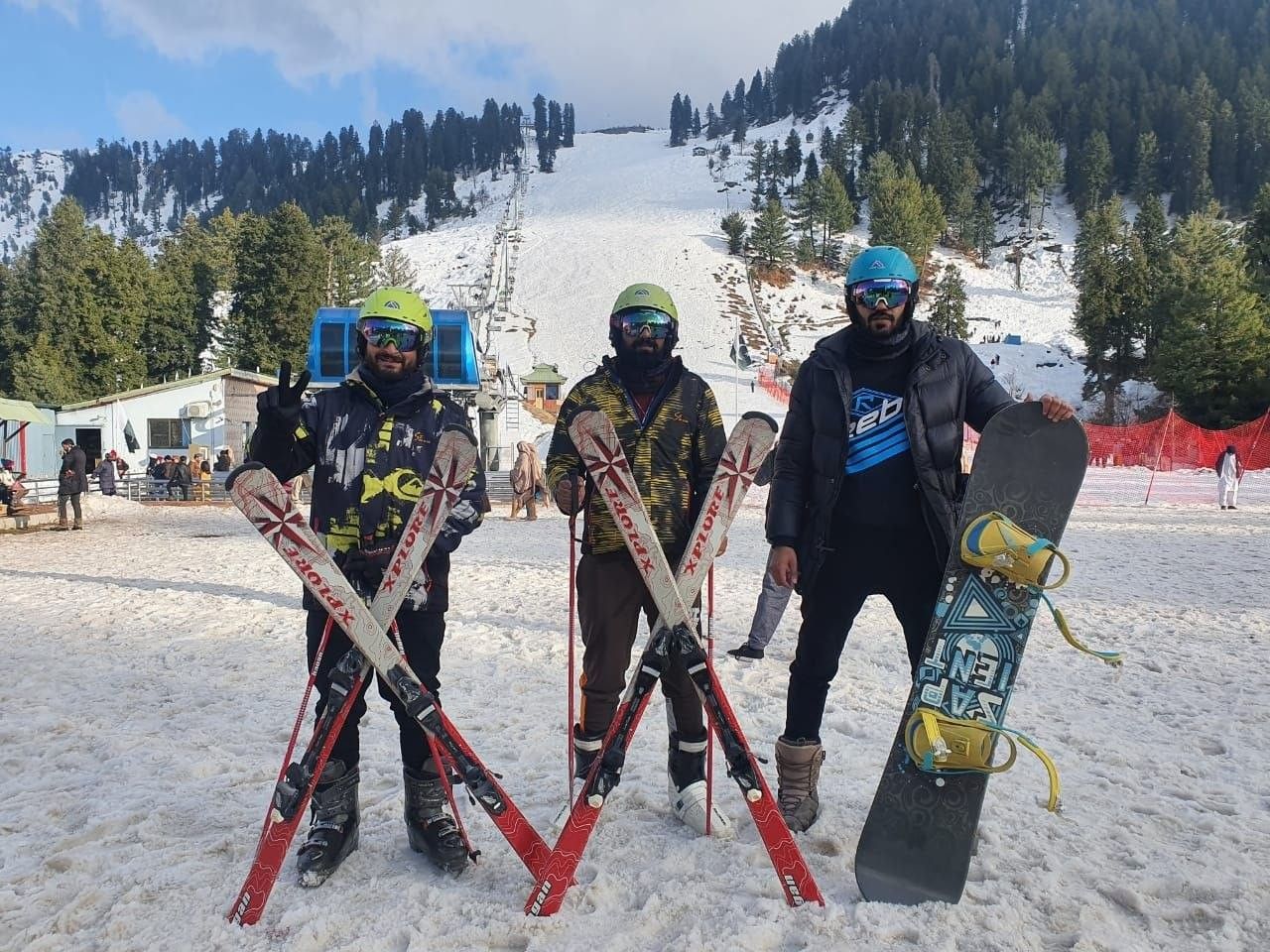 Skiers with skis and a snowboard on a snowy slope