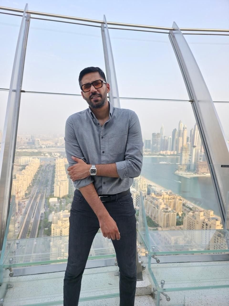Faaiz on a glass observation deck above a city skyline